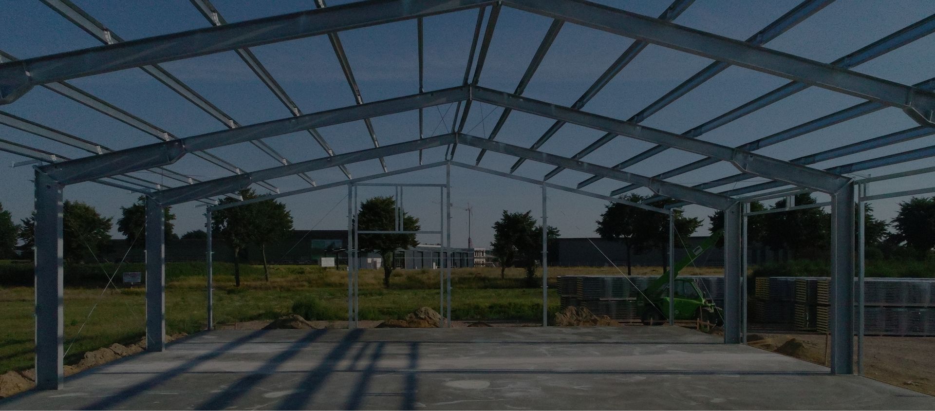 Offene Stahlrahmenkonstruktion einer Halle im Bau auf Grundstück im Grünen